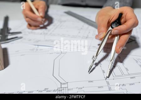 The architect measures with a dividers for drawing on paper. The designer draws a sketch of the project of the room. Stock Photo