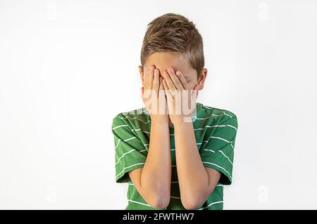 the ffightened boy covers his face with his hands on a white background Stock Photo