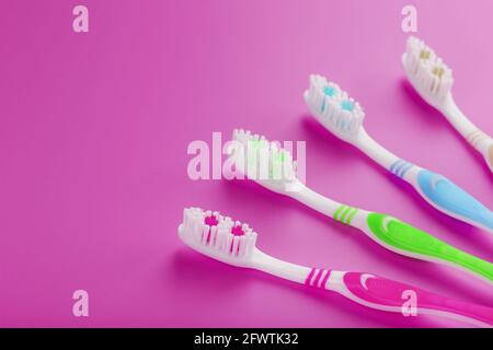 Four toothbrushes on a pink background in a row. Free space, isolate, top view Stock Photo