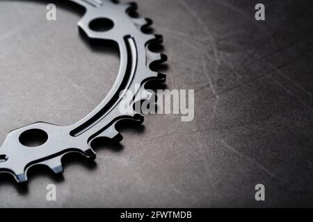 A black bicycle driving star with contrasting repeating cogs on a dark background. Bicycle parts and assemblies Stock Photo