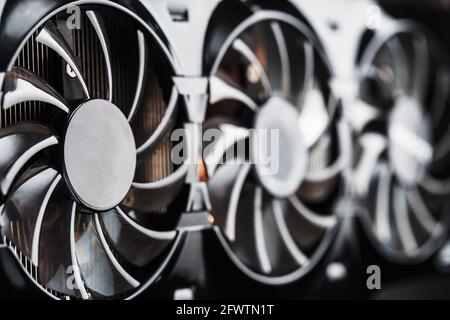 A video card with three fans is hardly a powerful cooling system. Video chip for gaming and cryptocurrency mining. Dark key Stock Photo