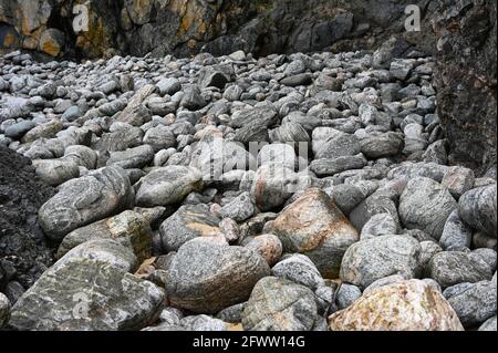 Abstract of large grey rocks at foot of black volcanic cliffs Stock Photo