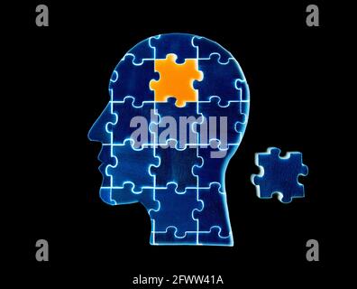 Blue human head shaped jigsaw puzzle with the final piece to be set in place isolated on black Stock Photo