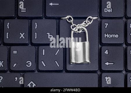 Close-up of a small locked padlock with a chain on a black laptop keyboard. Data security concept. Stock Photo