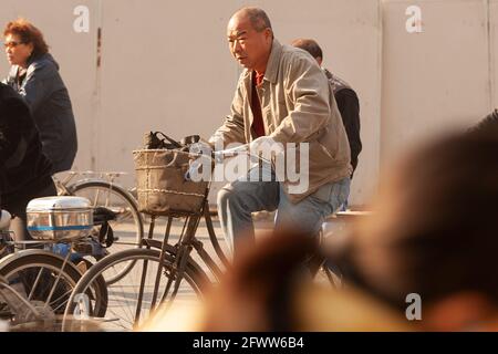 Shanghai, China, Asia - Old man riding a bicycle in the chaotic traffic of Shanghai. Stock Photo