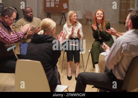 Happy people clapping hands after hot discussion of psychological problems at session Stock Photo