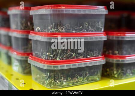Several stacks of plastic containers with nails on yellow shelf Stock Photo