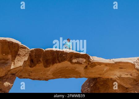 WADI RUM, JORDAN - MARCH 26, 2017: Tourist on Burdah rock bridge in Wadi Rum desert, Jordan Stock Photo