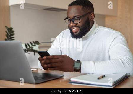 Young smiling african american man relaxing using laptop and mobile phone Stock Photo