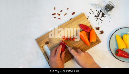 Male hands cutting peppers on a cutting board. Copy space. Stock Photo