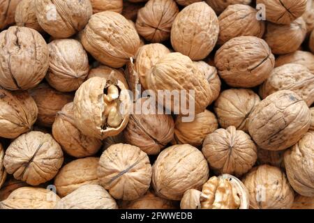 Walnut kernels and whole walnuts on rustic old wooden table. Stock Photo
