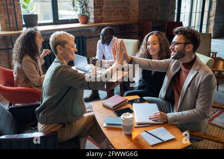 Successful colleagues giving each other high five over table in office Stock Photo