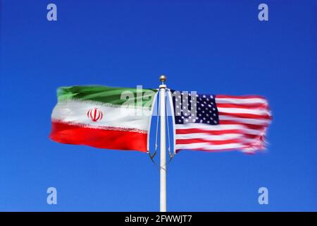 Iranian and American flags wave side-by-side in opposing winds on a single flagpole. Digital composite. Stock Photo