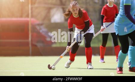 Teenage female field hockey player in attack with the ball. Young girl with he ball at field hockey game Stock Photo