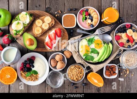 Healthy breakfast table scene with fruit, yogurts, oatmeal, smoothie, nutritious toasts and egg skillet. Top view over a wood background. Stock Photo