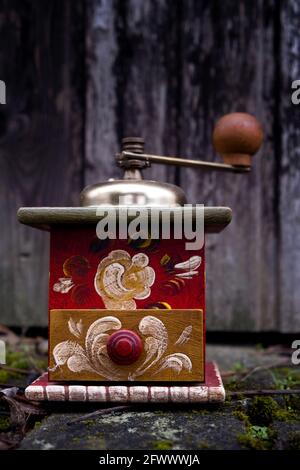 close-up of an old painted coffee grinder outsdie in front of weathered wooden door Stock Photo