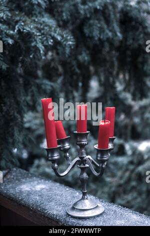 pewter candelabra with five red candles stands on ice outside in winter Stock Photo
