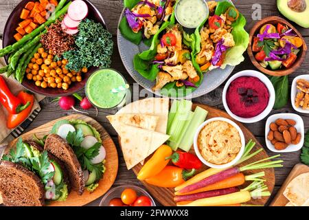 Healthy lunch table scene with nutritious Buddha bowl, lettuce wraps, vegetables, sandwiches and salad. Above view over a wood background. Stock Photo