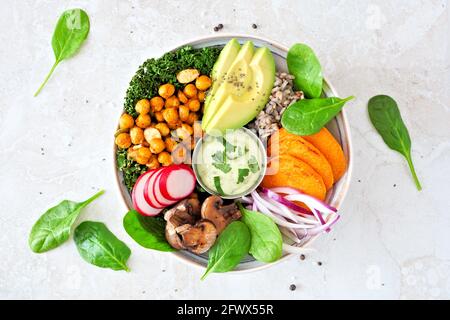 Healthy vegan lunch bowl with avocado, sweet potato, kale and vegetables. Top view on a white stone background. Healthy eating concept.