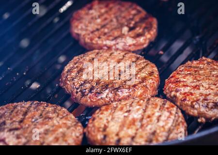 Beef burgers for hamburger on metal barbecue grill close-up. Party BBQ day Stock Photo