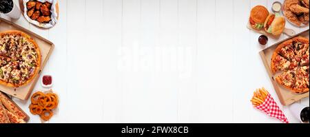 Assortment of take out or delivery  foods. Pizza, hamburgers, fried chicken and sides. Double side border. Top view on a white wood banner background Stock Photo