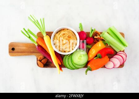 Selection of fresh vegetables and hummus dip on a serving tray. Above view on a white marble background. Stock Photo