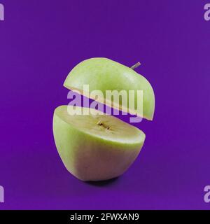 Sliced green apple floating on trendy lavender background. Ultra violet color. Minimal abstract food and fruits concept. Stock Photo