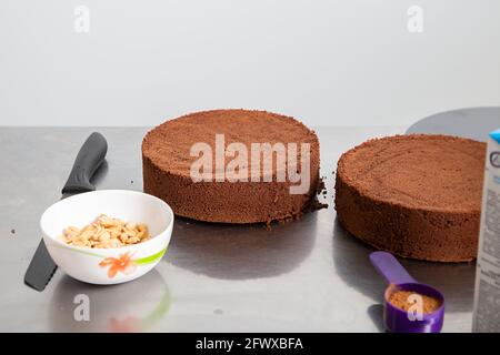 Front side view of two thick layers of baked chocolate sponge cake on metal table. Making Chocolate Layer Cake. Series. Stock Photo