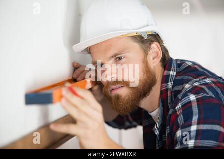 concentrated man using spirit level on wall Stock Photo