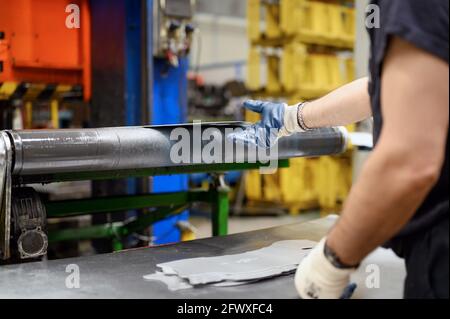 Close-up of male hands in working gloves working in metal processing factory. Worker using machinery in Steel industry, manufacturing, production. High quality photo Stock Photo
