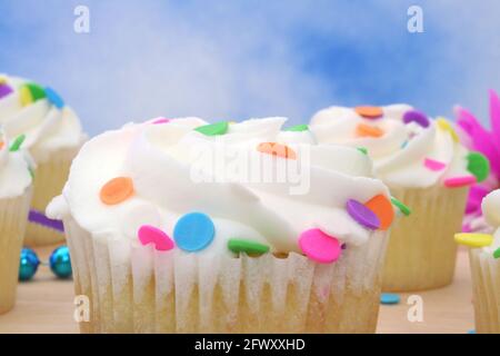 Cupcakes with brightly colored sprinkles on blue background Stock Photo