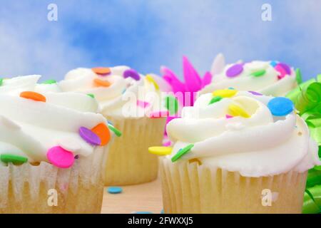 Cupcakes with brightly colored sprinkles on blue background Stock Photo