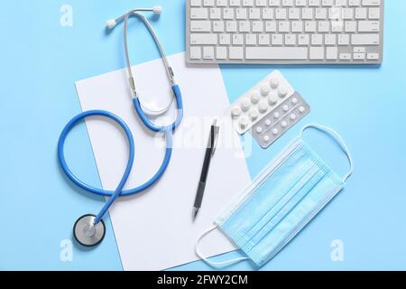 Composition with modern stethoscope, computer keyboard, pills and mask on color background Stock Photo