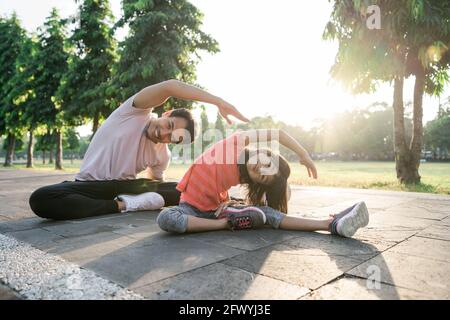 father and little daughter do exercises in outdoor. Healthy lifestyle of family with child Stock Photo
