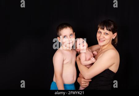 Family are looking at camera posing. Young woman and her two children. Stock Photo