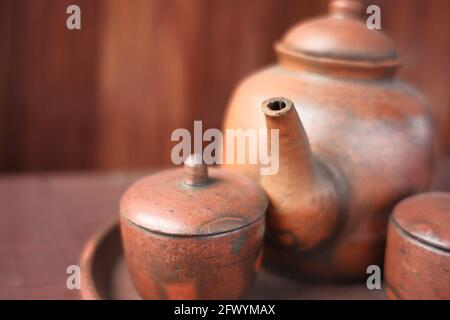 kettles and glasses handmade with clay materials. traditional Javanese kitchen tools used for warm drinks. Indonesian red kitchen utensil on a wooden Stock Photo