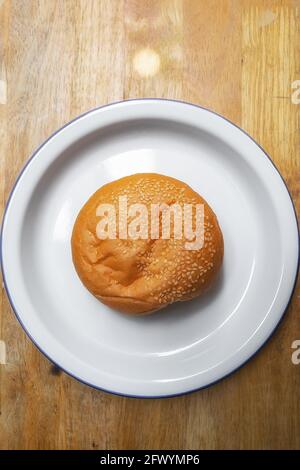 soft round fresh golden brown sesame seed hamburger bun in white dish on wood table Stock Photo