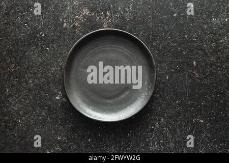Empty vintage plate on black table. Top view. Stock Photo