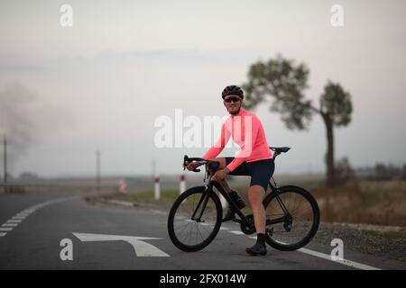 Young man sitting on bike smiling and looking at camera Stock Photo