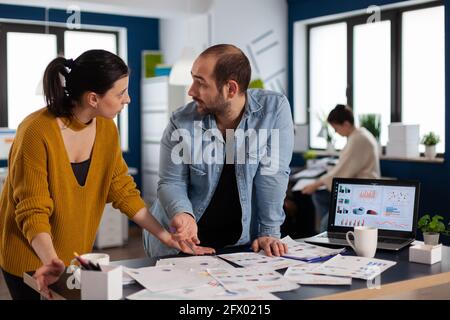 Multiethnic entrepreneurs brainstoriming charts data in office looking at each other. Diverse team of business people analyzing company financial reports from computer. Successful start up corporate professional entrepreneur online internet statistics Stock Photo