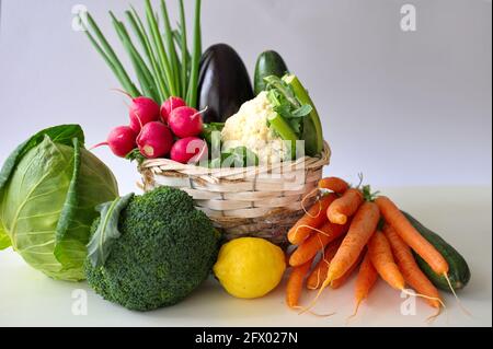 Healthy vegetables in wicker basket on white table Stock Photo