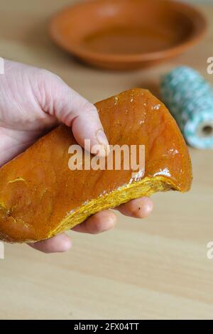 Pork meat marinated in soy sauce and spices. The hand holds a large, appetizing piece of pork loin. The meat is ready for dry-aged. An empty clay plat Stock Photo