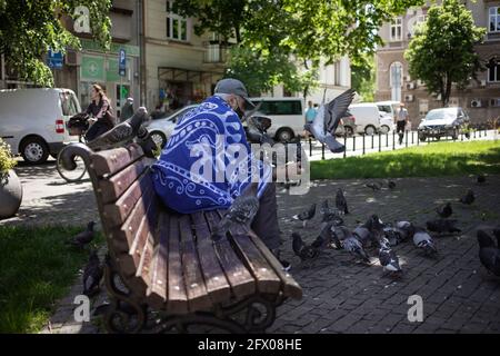 Belgrade, Serbia, May 23, 2021: Senior citizen feeding pigeons in the park Stock Photo