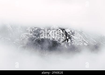 Invisible dark rocky ridge of mountains of Peaks of Europe covered with snow in heavy fog Stock Photo