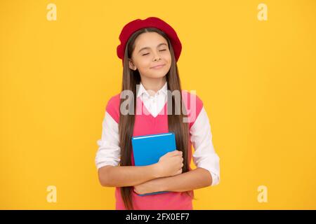 dreamy teen school girl in french beret hold copybook on yellow background, dream Stock Photo