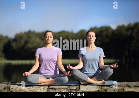F4ront view portrait of two women practicing yoga in the mountain Stock Photo