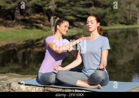 Woman teaching yoga exercise to another female outdoors in a lake Stock Photo