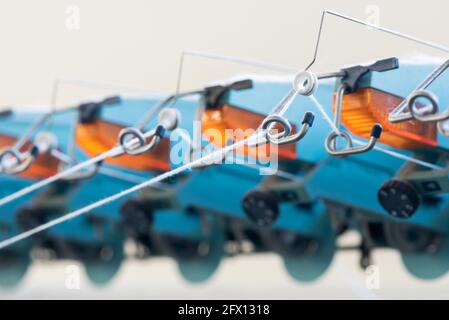 Close up detail of a knitting machine in a factory threaded with white yarn through the steel guides or eyes in a manufacturing concept Stock Photo