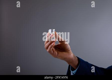 Close up of businessman holding bulb screw base against grey background Stock Photo