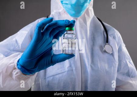 Mid section of health worker wearing protective clothes covid-19 vaccine bottle Stock Photo